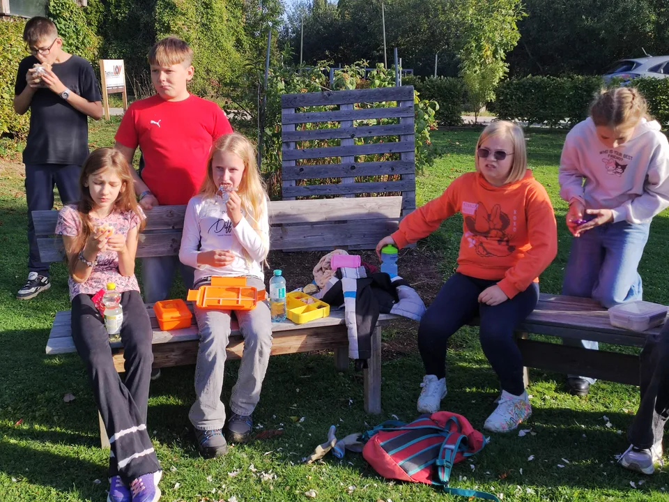Schüler*innen machen auf Holzbänken im Garten Jause
