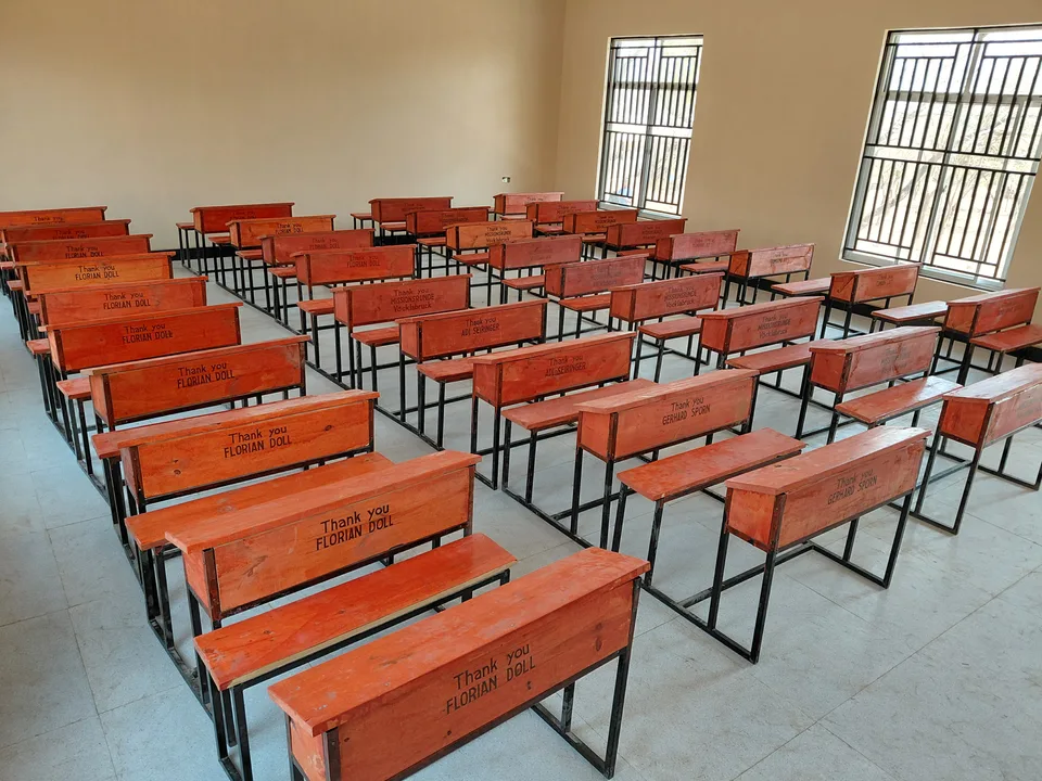 Reihen neuer Schulbänke mit eingravierten Namen in einem hellen Klassenzimmer